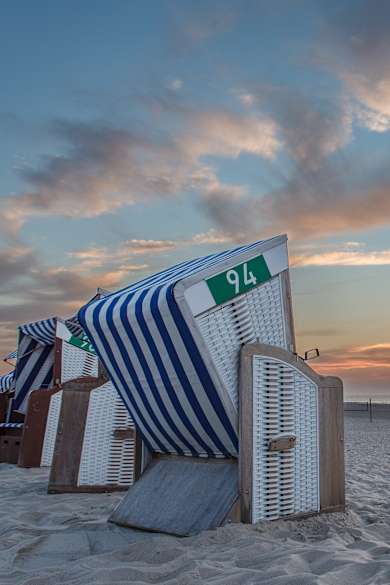 Strandkörbe an einem Strand bei Sonnenuntergang